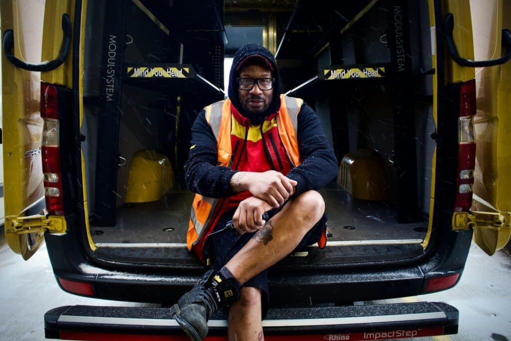 a man sitting on the back of a yellow van